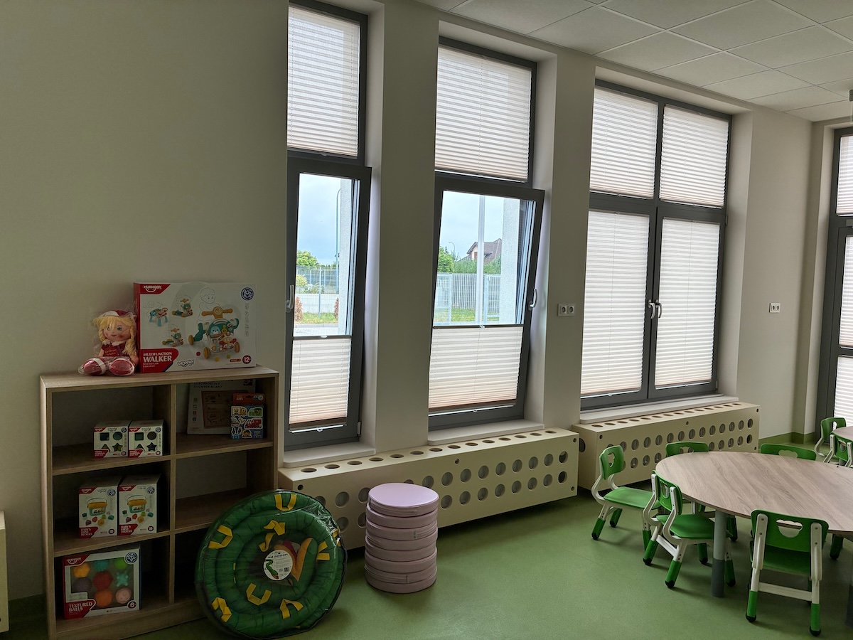 Sala z dużymi oknami, zabawkami i zielonymi krzesełkami